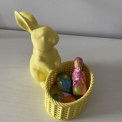 Estatueta de coelho amarela com cesto amarelo e ovos de chocolate coloridos