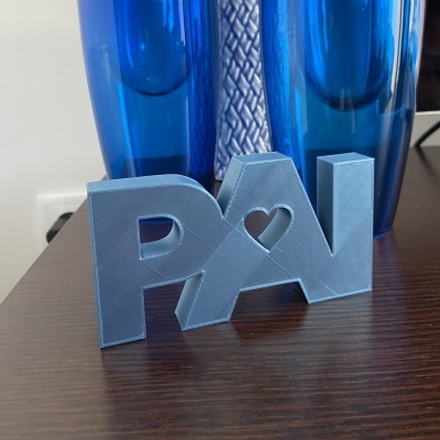 Figura decorativa azul com letras PAI e coração recortado sobre mesa de madeira e vasos azuis ao fundo