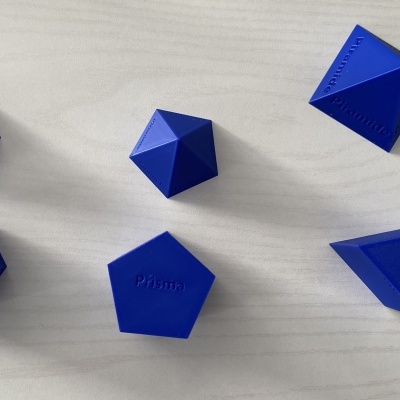Prismas geométricos azuis com inscrições sobre superfície de madeira clara