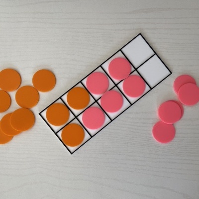 Fichas de jogos tabuleiro laranja e rosa sobre tabuleiro rectangular e superfície de madeira