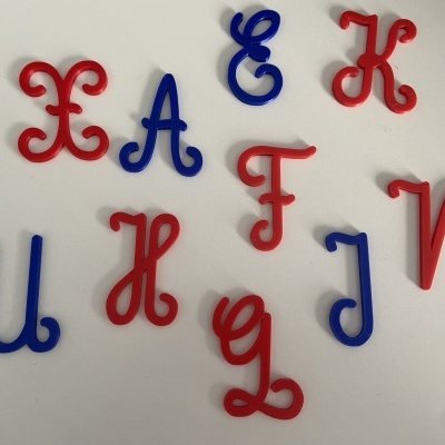 Letras plásticas decorativas vermelhas e azuis sobre fundo branco