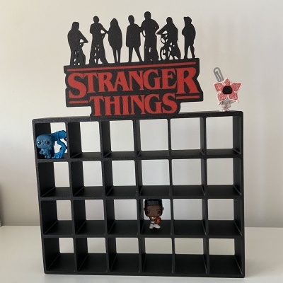 Expositor preto de figuras com logotipo vermelho STRANGER THINGS e três figuras colecionáveis.