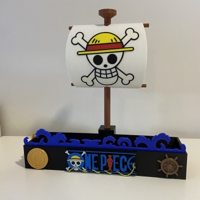 Miniatura de barco pirata com vela e base decorada com o logo One Piece.