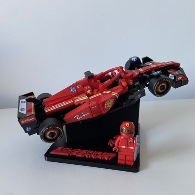 Modelo LEGO de carro de Fórmula 1 vermelho com minifigura e suporte preto com texto Ferrari