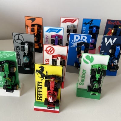 Miniaturas de carros de Fórmula 1 com suportes coloridos e nomes das equipas