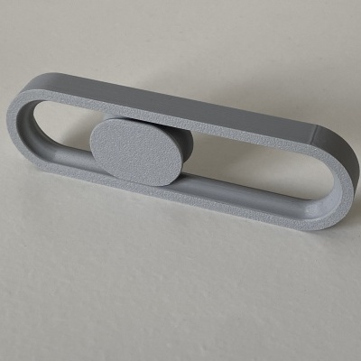 Peça ovalada cinzenta em plástico texturizado sobre superfície cinzenta