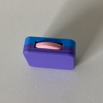 Laço estilizado de plástico azul, roxo e rosa sobre superfície branca