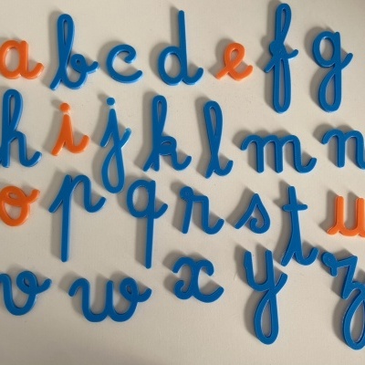 Letras do alfabeto em plástico azul e laranja sobre fundo branco.