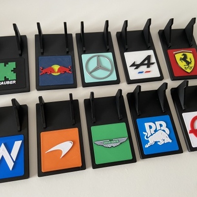 Suportes pretos para telemóveis com logotipos de equipas de Fórmula 1