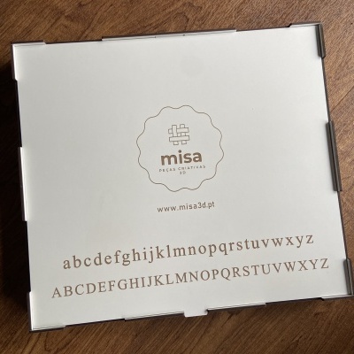 Embalagem branca quadrada com texto e logotipo Misa sobre madeira