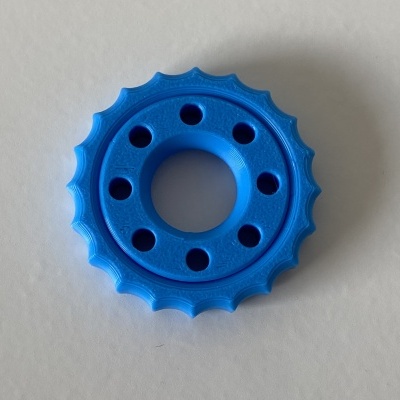 Peça plástica azul circular com orifícios sobre fundo branco