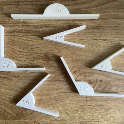 Esquadros de plástico branco com ângulos variados sobre mesa de madeira