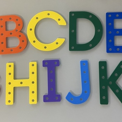 Letras coloridas do alfabeto em plástico com buracos sobre superfície cinza