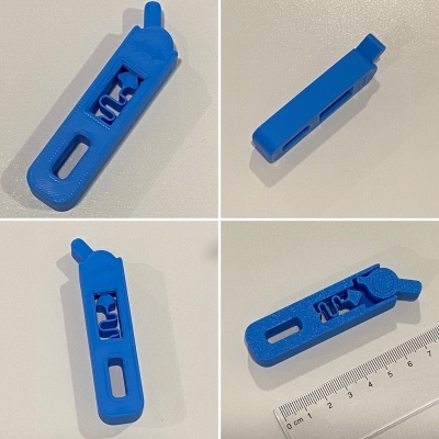 Peça azul de plástico com fenda e mecanismo, vista sob vários ângulos com régua para escala.