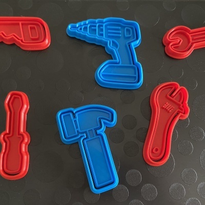 Cortadores de biscoitos em forma de ferramentas coloridos sobre superfície preta