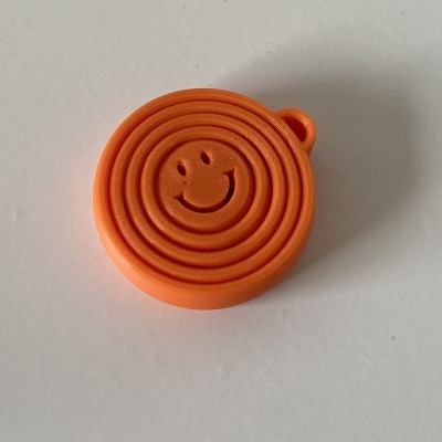 Objeto plástico circular laranja com rosto sorridente em relevo