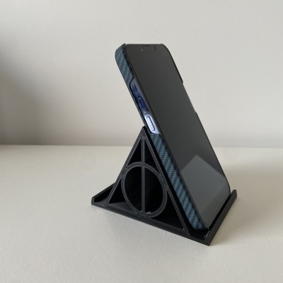 Smartphone com capa segurado por suporte preto triangular em superfície clara