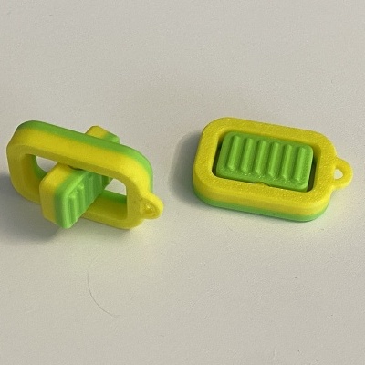 Dois pequenos objetos amarelos e verdes de plástico com textura estriada sobre fundo branco