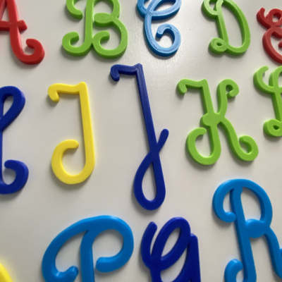 Várias letras do alfabeto maiúsculas coloridas em plástico sobre fundo branco