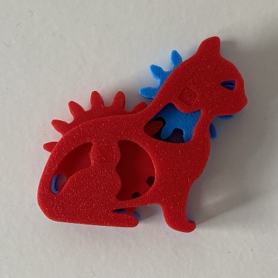 Boneco plástico vermelho e azul em forma de dinossauro sobre fundo branco