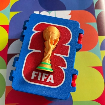 Estojo plástico azul com relevo dourado de taça e letras FIFA vermelhas