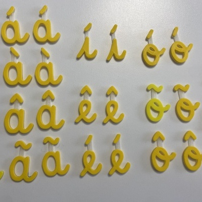 Caracteres alfabéticos acentuados em plástico amarelo sobre fundo branco