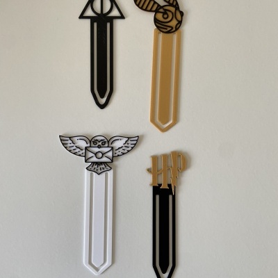 Quatro marcadores de livro com símbolos de Harry Potter em várias cores montados numa parede branca