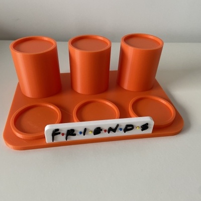 Suporte laranja com copos e placa com texto FRIENDS