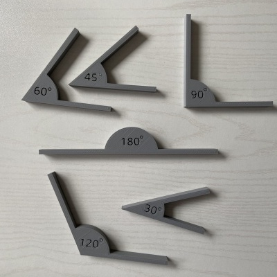 Conjunto de esquadros cinzentos com ângulos variados sobre superfície branca