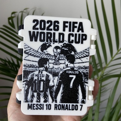 Caixa branca com desenho preto da FIFA World Cup 2026 e jogadores Messi e Ronaldo