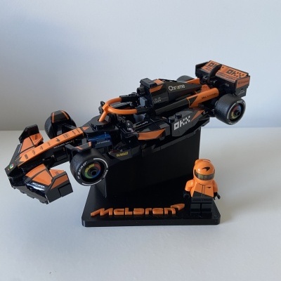 Miniatura de carro de Fórmula 1 McLaren preto e laranja com figura de corredor e base preta