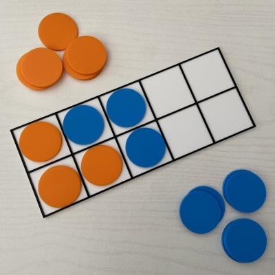 Placa de jogo com fichas laranja e azul sobre mesa clara