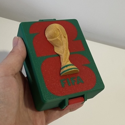 Caixa plástica verde com detalhe da taça da FIFA e números 23 vermelhos no tampo.