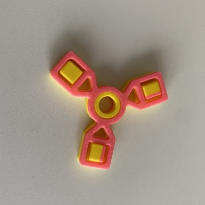 Spinner de três braços cor de rosa e amarelo sobre superfície branca