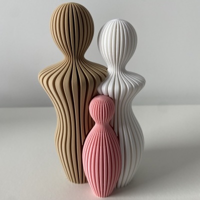 Três esculturas decorativas abstratas em bege, branco e rosa num fundo claro