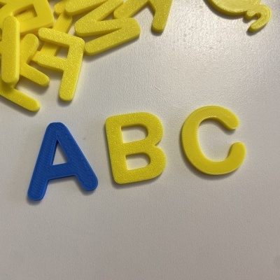 Letras de espuma azul e amarelas na superfície branca