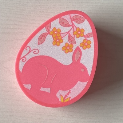 Caixa em forma de ovo com coelho cor-de-rosa e flores amarelas e rosadas