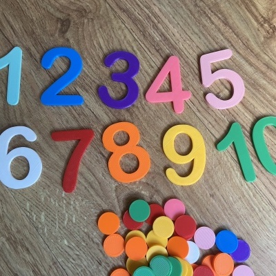 Números plásticos coloridos de 1 a 10 e discos coloridos em fundo de madeira.