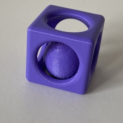 Objeto 3D roxo em forma de cubo com esfera suspensa dentro