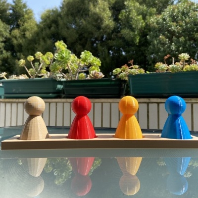 Figuras de madeira coloridas em base de madeira numa mesa de vidro com plantas ao fundo