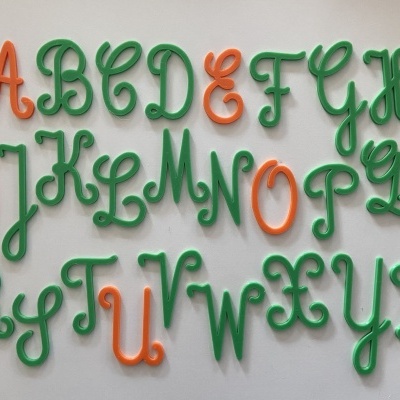 Letras do alfabeto coloridas em plástico verde e laranja
