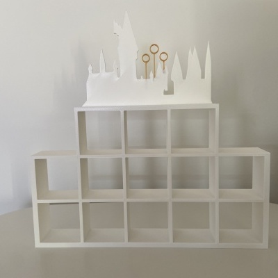 Estante branca de madeira com escultura branca e pinos dourados no topo