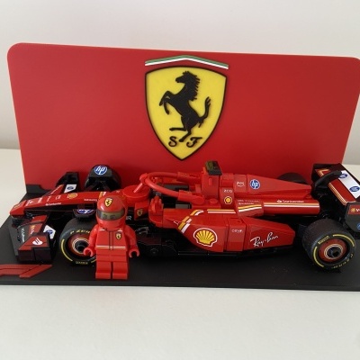 Modelo de carrinho de corrida Ferrari de LEGO com minifigure e logo da Ferrari ao fundo