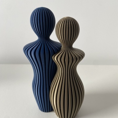 Dois objetos decorativos humanoides azul e castanho com textura estriada em fundo branco