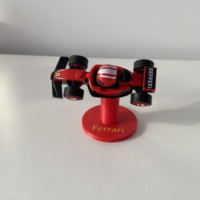 Miniatura de carro de Fórmula 1 Ferrari vermelho em suporte vermelho com texto Ferrari