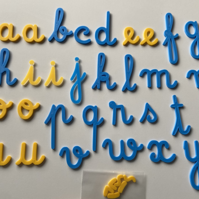 Letras de plástico amarelas e azuis em estilo cursivo num fundo branco