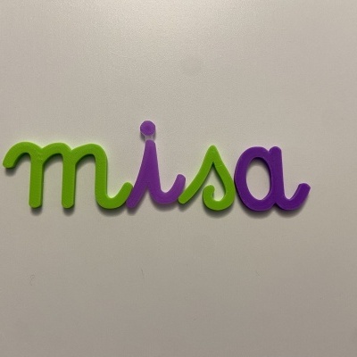 Palavra 'misa' em letras coloridas verde e roxo numa superfície branca