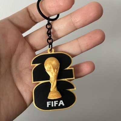 Porta-chaves com figura da Taça do Mundo FIFA dourada sobre fundo preto com números 2 e 6