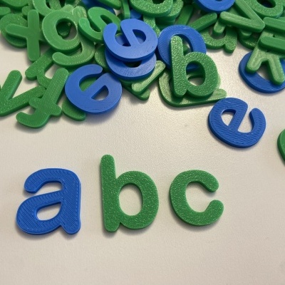 Letras de alfabeto em plástico verde e azul sobre superfície branca