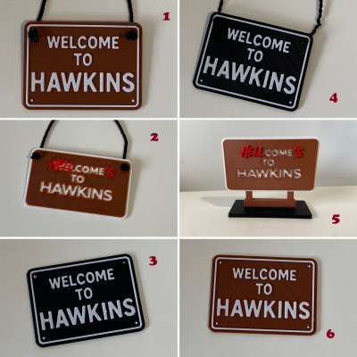 Seis placas decorativas plásticas com frases WELCOME TO HAWKINS e HELL COMES TO HAWKINS em castanho e preto.